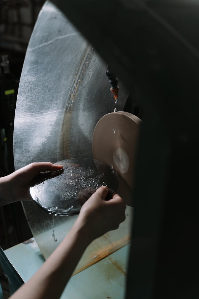 why-choose-us Close-up of hands cutting glass on an industrial machine in a workshop setting.